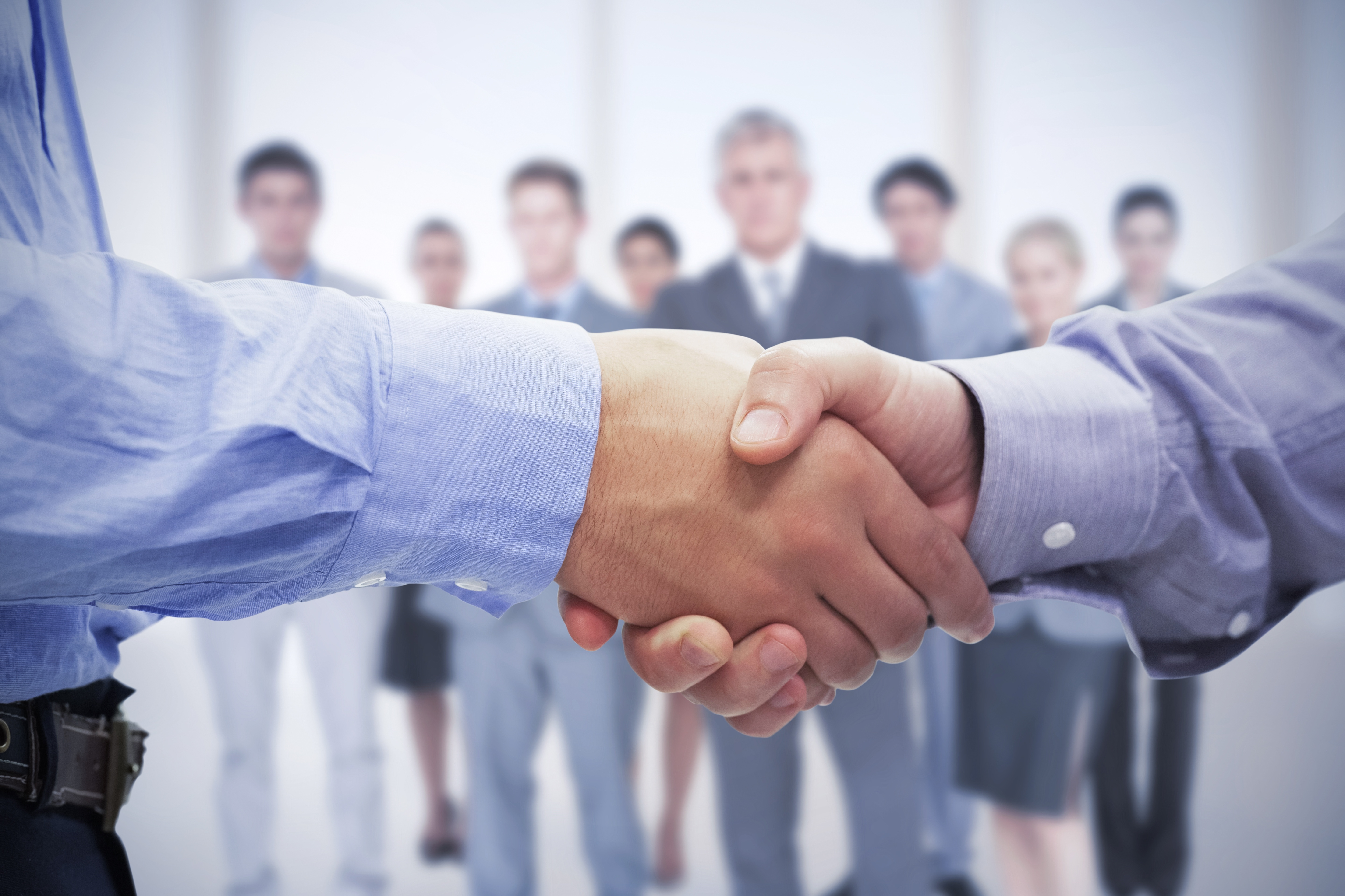 Close up of handshake with people in the background